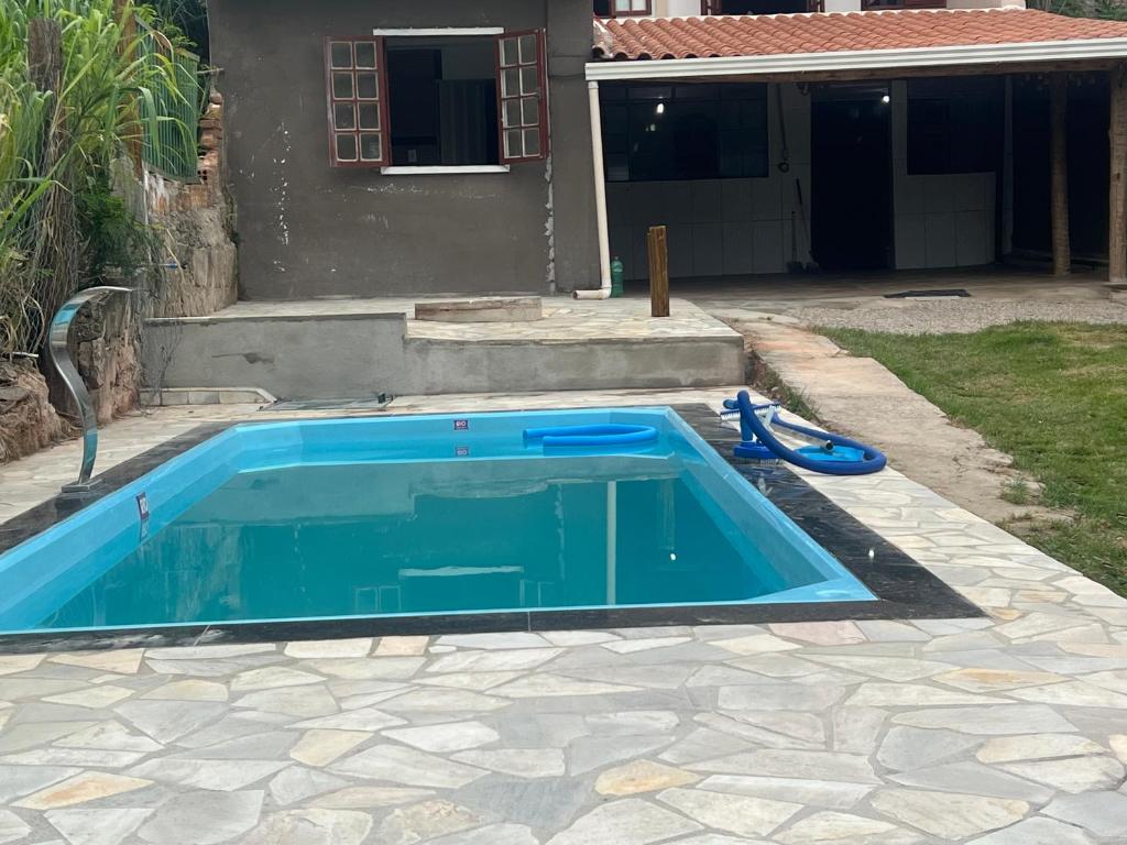 una piscina azul en un patio junto a una casa en Espaço Diniz, en Santa Luzia
