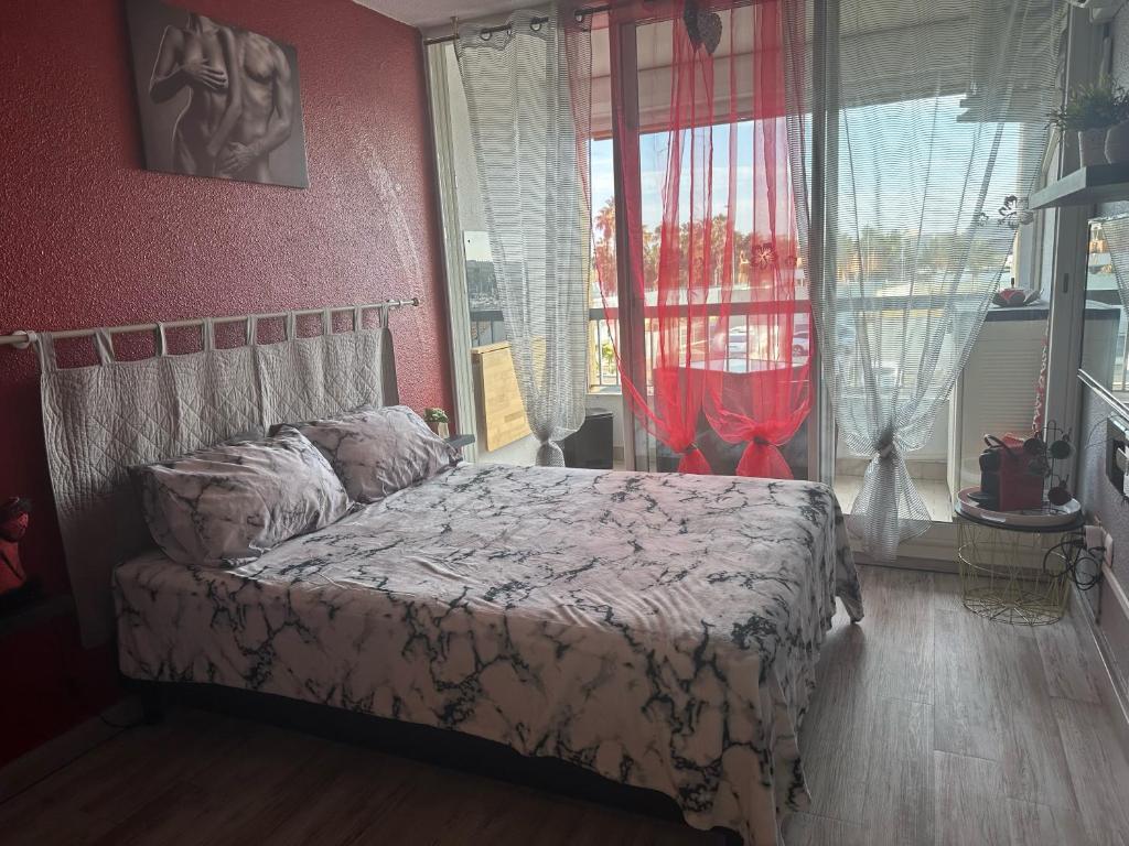une chambre avec un lit et une grande fenêtre dans l'établissement Village naturiste - Studio Port-Soleil - Le rouge, au Cap d'Agde