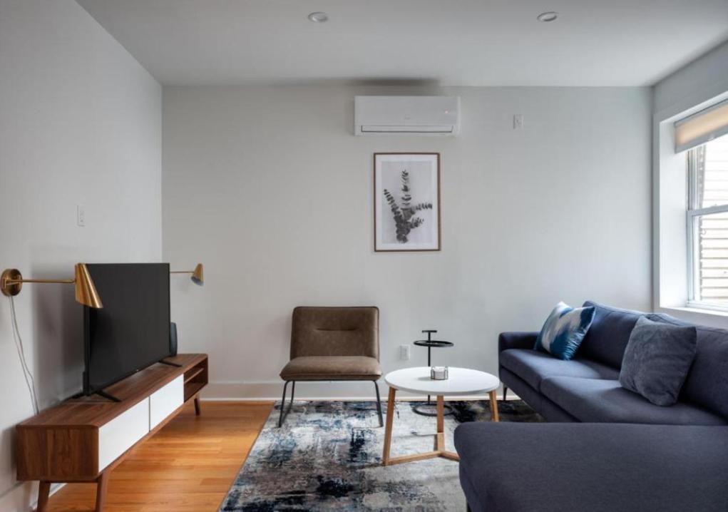 Splendid 2 Bedroom apartment in NYC! في نيويورك: غرفة معيشة مع أريكة زرقاء وتلفزيون