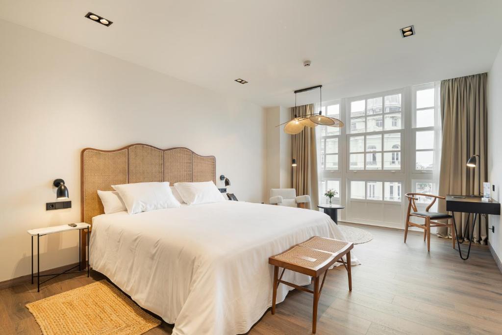 a white bedroom with a large bed and a desk at Sercotel EsteOeste in Lugo