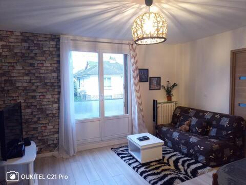 a living room with a couch and a large window at Superbe chambre confortable et lumineuse en appartement in Bry-sur-Marne