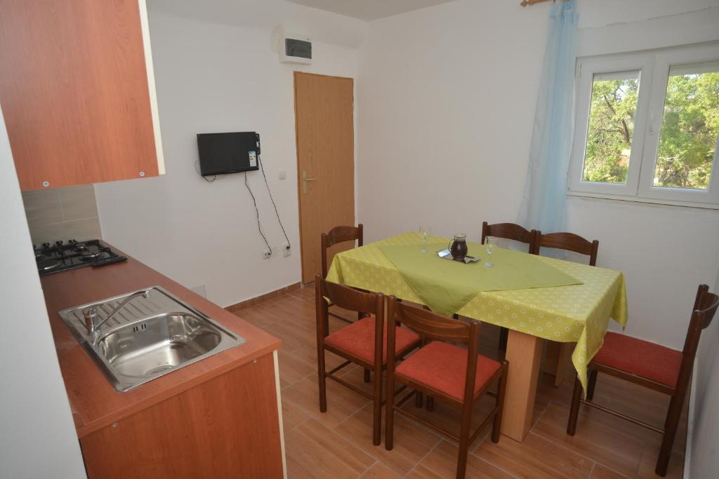 una pequeña cocina con mesa, sillas y fregadero en Apartments Citrus, en Turanj