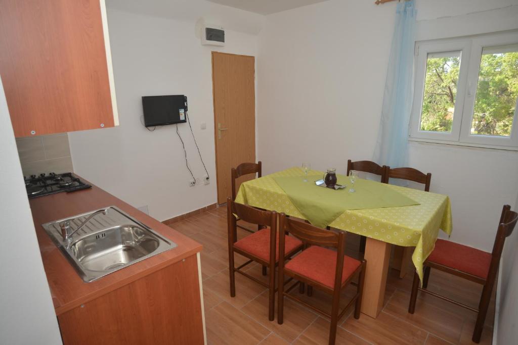 a small kitchen with a table and chairs and a sink at Apartments Citrus in Turanj