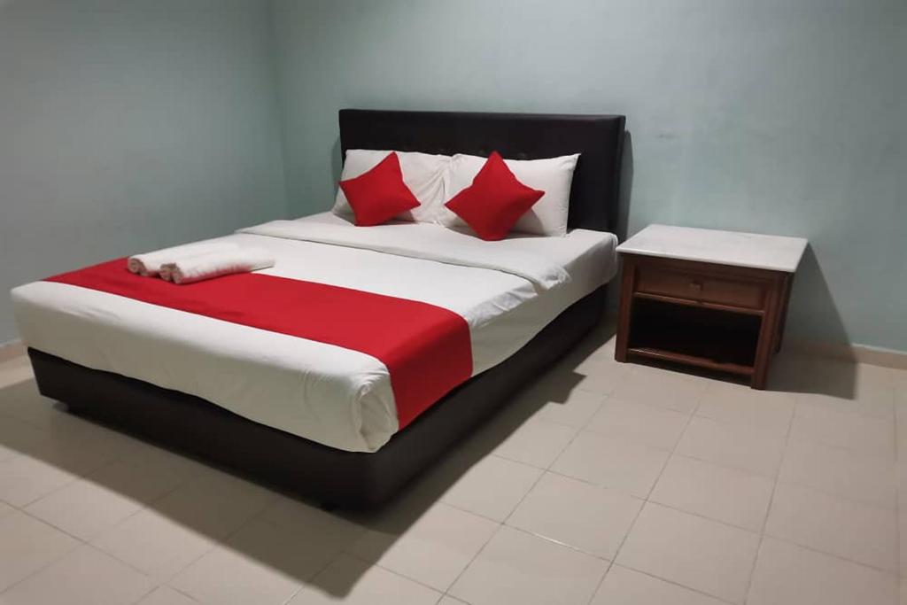 um quarto com uma cama com almofadas vermelhas e brancas em Langkawi Tok Jah Guest House em Pantai Cenang