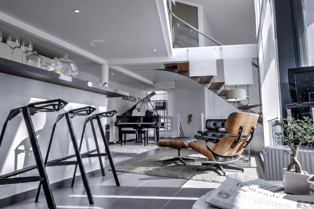 een woonkamer met een trap, een stoel en een piano bij Beautiful Loft 130m2 Sun and free parking in La Garenne-Colombes