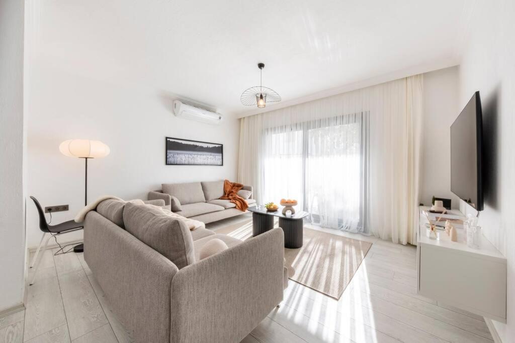 a white living room with a couch and a tv at Bodrum Center 2 Bedroom Calm Modern Garden Floor Flat - Yeni Dünya Bodrum in Bodrum City