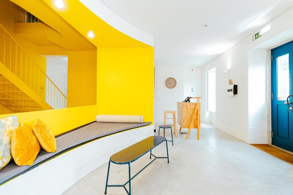 a room with yellow walls and a bench with yellow pillows at Surf & Sea Suites in Parede