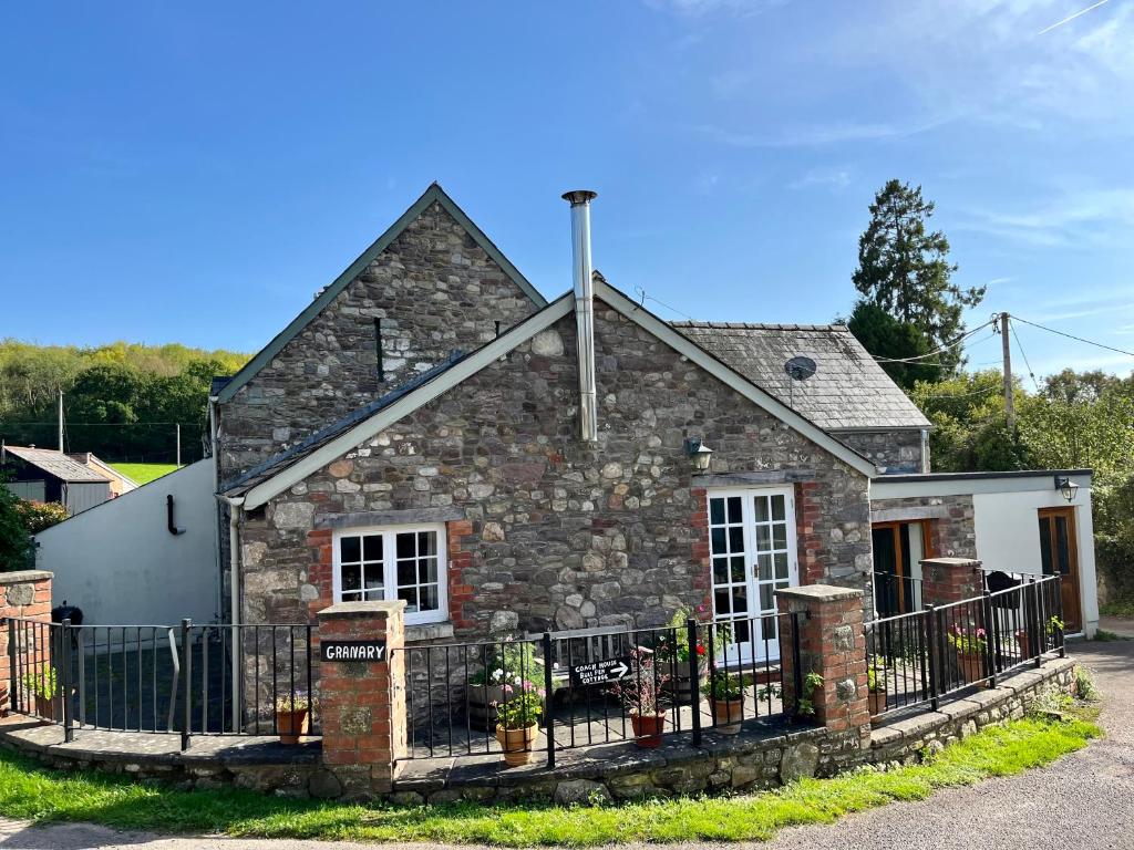 una casa de piedra con una valla delante de ella en The Granary en Abergavenny