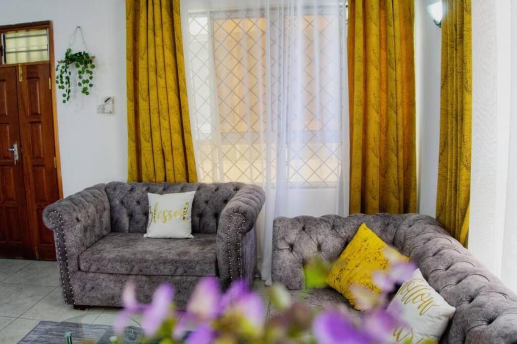 a living room with two couches and yellow curtains at 3 bedroom furnished apartment at Kings Square in Eldoret