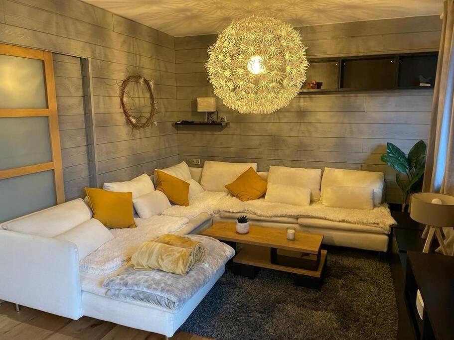uma sala de estar com um sofá e um lustre em Joli logement 6 à 8 pers avec terrasse La Cigale em Orbey