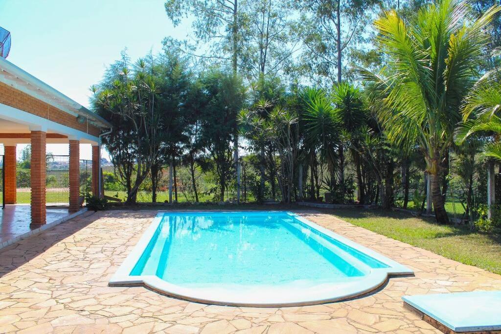 a swimming pool in a yard with palm trees at Espaço Geraldo Meirelles in Casa Branca