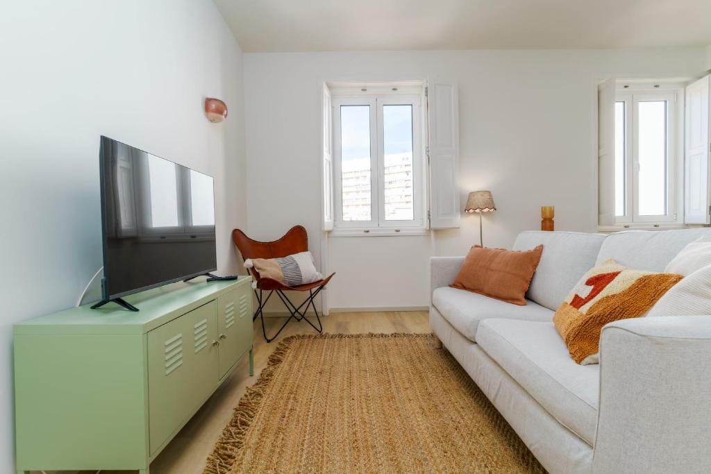 een woonkamer met een witte bank en een tv bij Modern & Cozy Faro Mercado Apt 21 in Faro