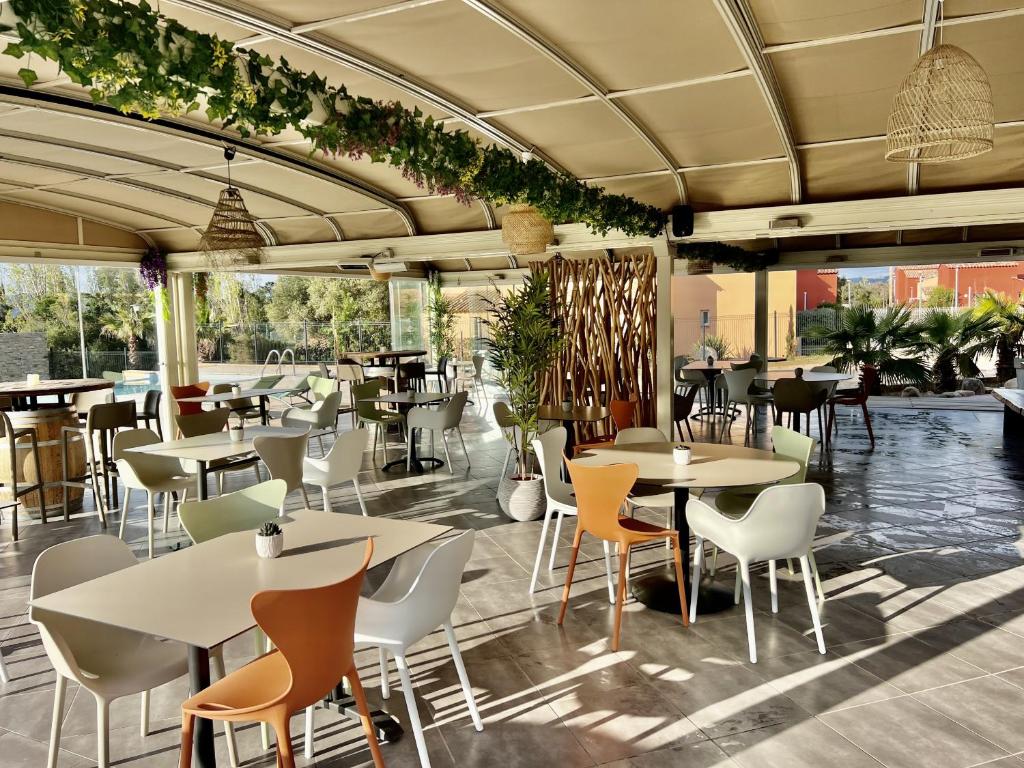 un ristorante con tavoli e sedie e un patio di Résidence hôtelière les hameaux de saint cyprien appartement 25 M2 1 chambre a Lecci