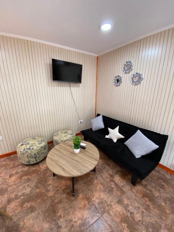 sala de estar con sofá negro y mesa en Arriendo de cabaña centro osorno en Osorno