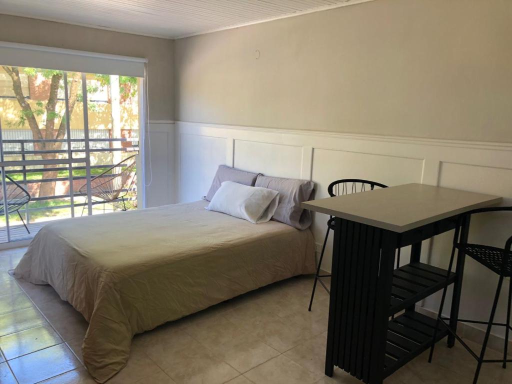 1 dormitorio con cama, mesa y ventana en La Comarca Aparts Alojamiento en Colón