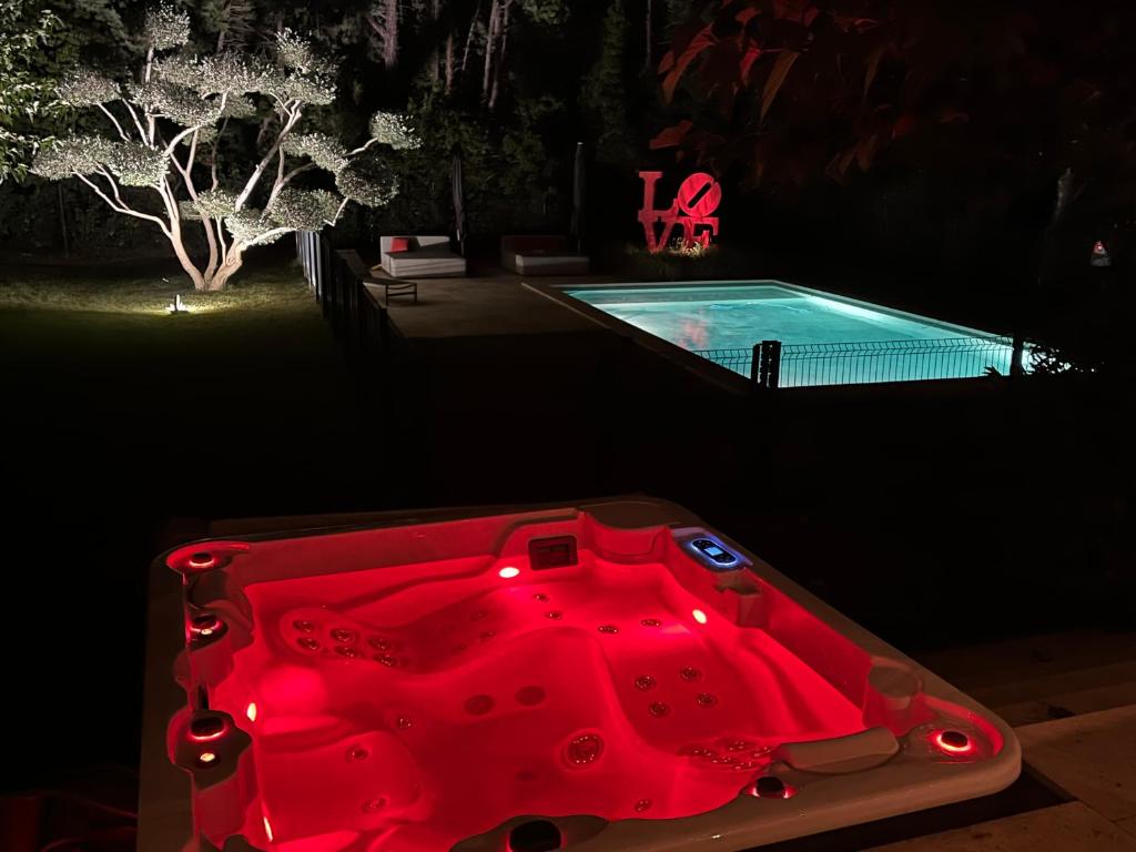 uma piscina com uma mesa vermelha em frente em Domaine de La Franquette by Bridget & Pascal em Caderousse