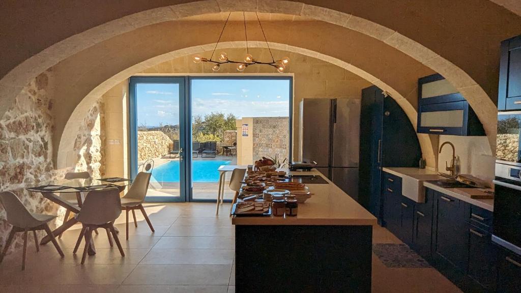 eine Küche mit einem Tisch und ein Esszimmer mit einem Pool in der Unterkunft Sea Holly Gozo in Nadur