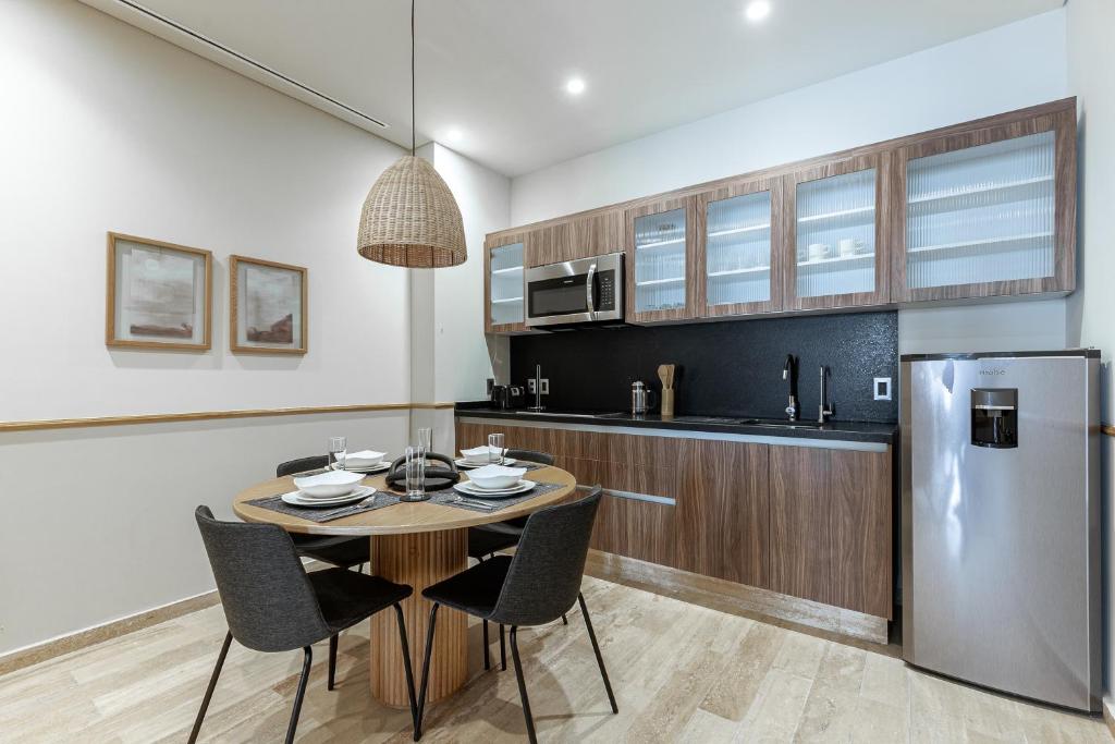 A compact fitted kitchen with a four-seat dining table and full-size refrigerator.