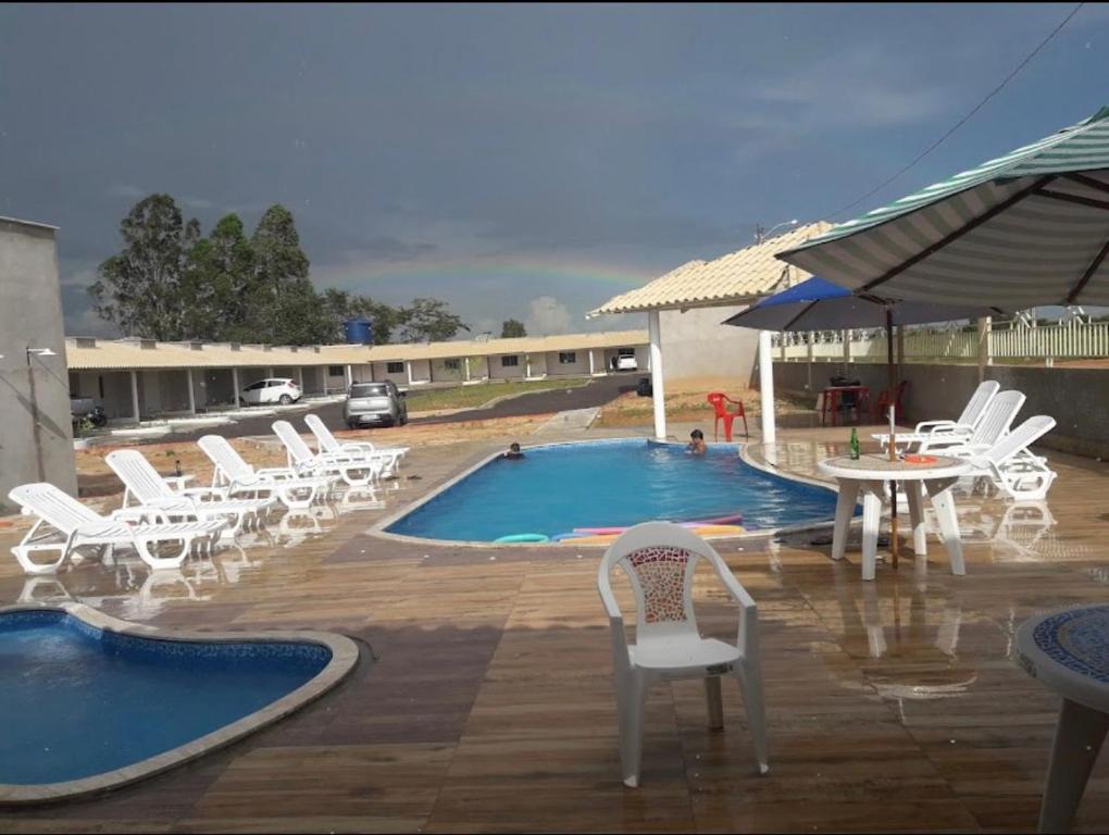 una piscina con sillas blancas, una mesa y una piscina en Carolina Palace Hotel, en Carolina