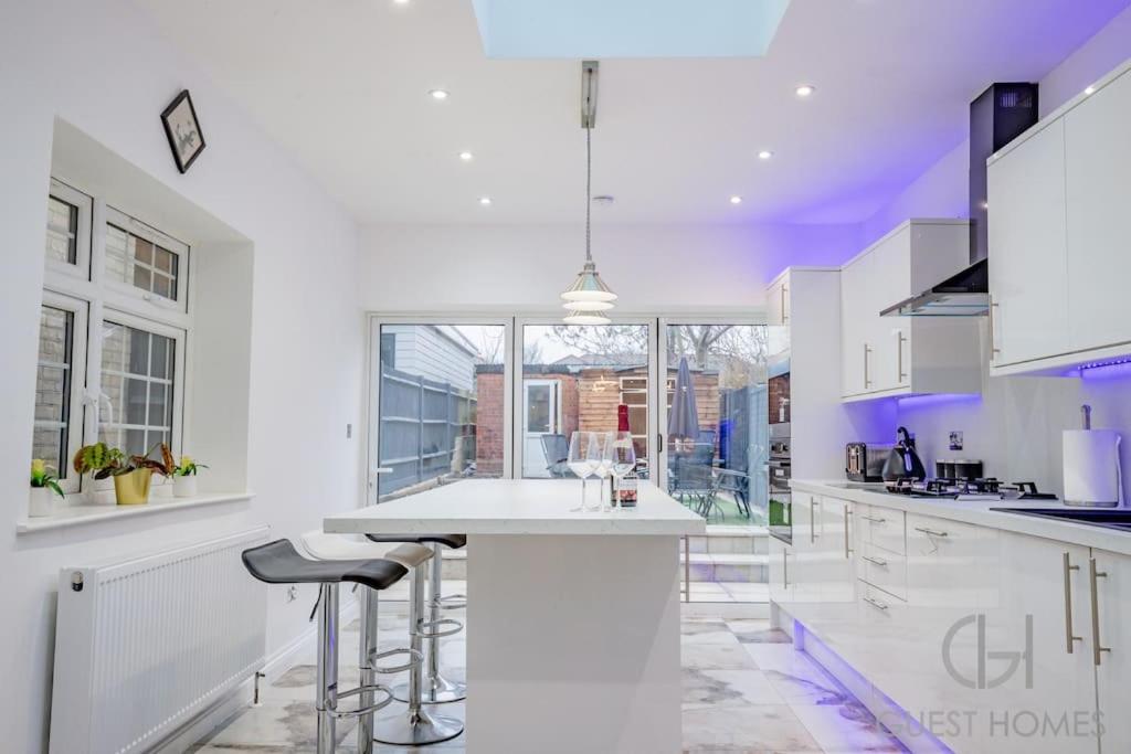 a white kitchen with a white counter and stools at Guest Homes - Broadland House in Southampton