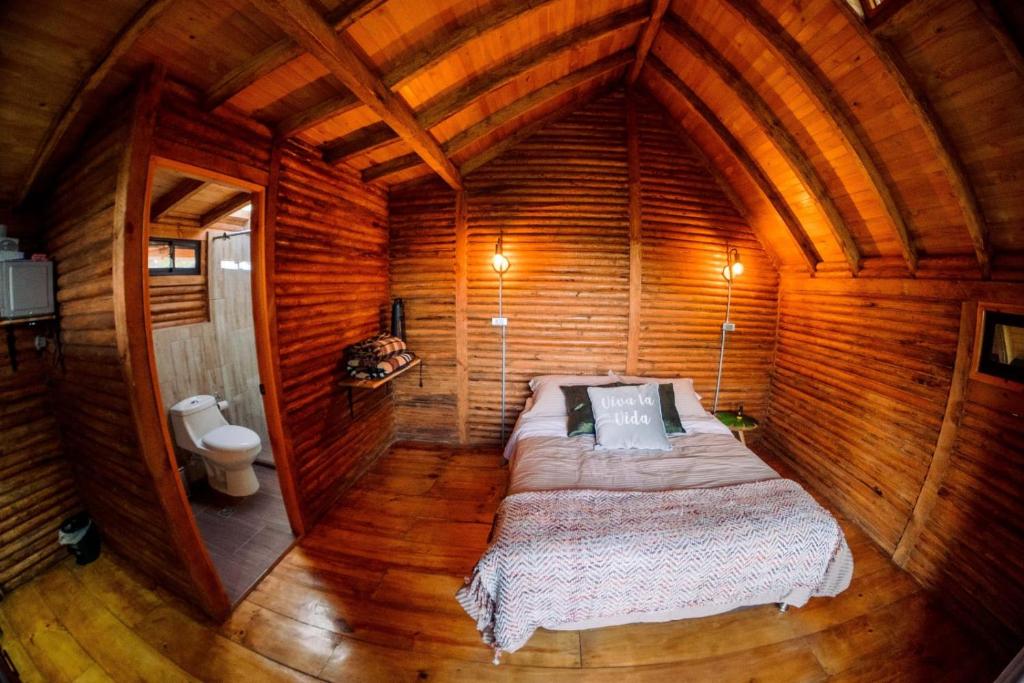 ein Schlafzimmer mit einem Bett in einer Holzhütte in der Unterkunft Ecoverso Cabañas del bosque in Medellín