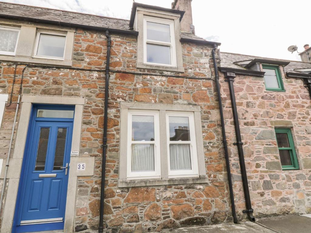 ein Backsteinhaus mit blauer Tür und Fenstern in der Unterkunft Haven Cottage in Kirkcudbright