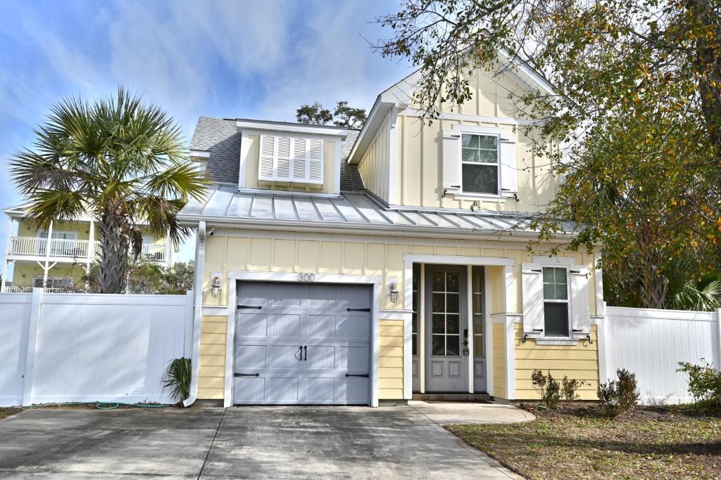 una casa amarilla con una valla blanca y un garaje en Spacious House near the Beach 300 en Myrtle Beach