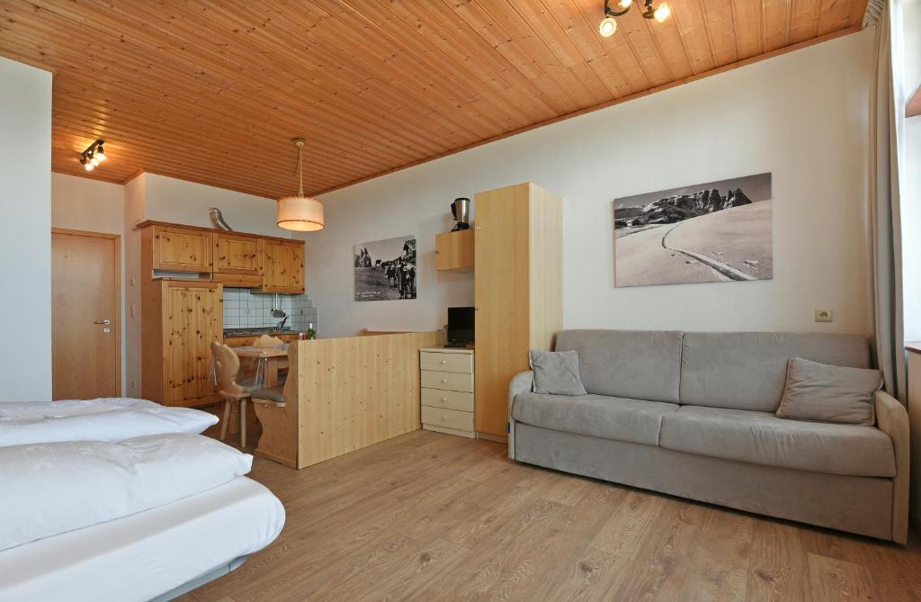 um quarto com uma cama, um sofá e uma cozinha em Appartaments Alpi em Seiser Alm