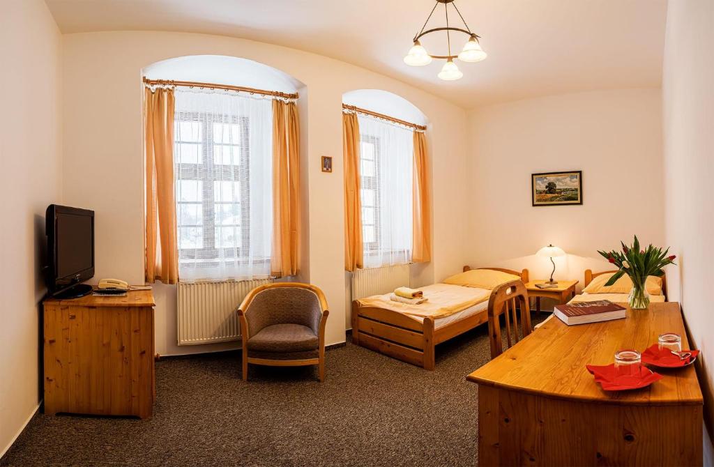 a living room with a bed and a table at Klášter Hejnice - vzdělávací, konferenční a poutní dům in Hejnice