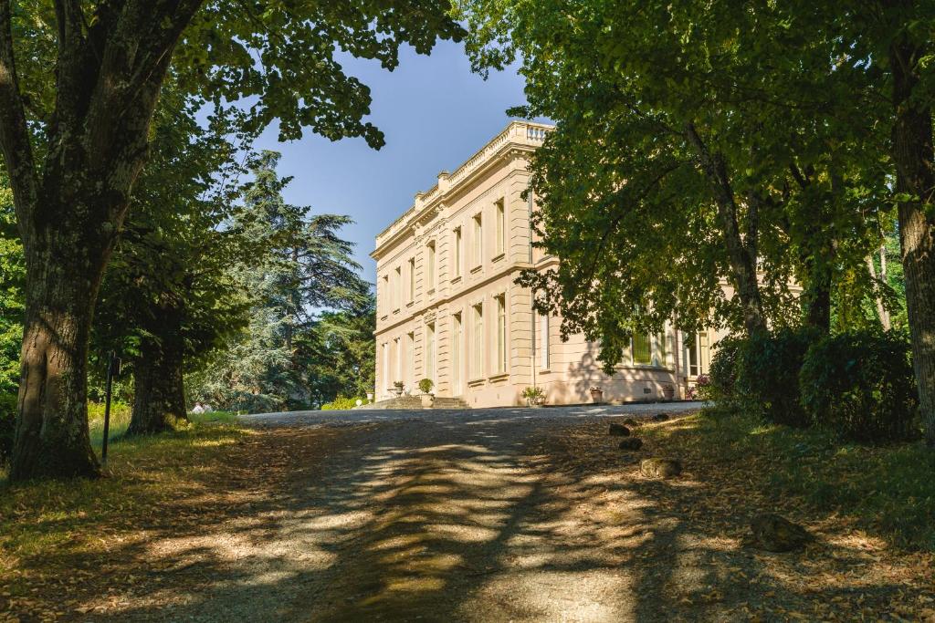 un gran edificio blanco con árboles delante de él en Maison d'hôtes - Villa Les Pins - Lempaut, en Lempaut