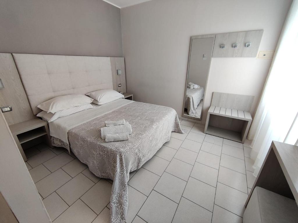 una camera bianca con letto e specchio di Hotel Stefan Room & Breakfast a Gatteo a Mare