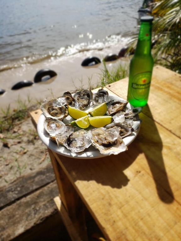 un plato de ostras en una mesa junto a una botella en Frente ao Mar, en Ilha Comprida