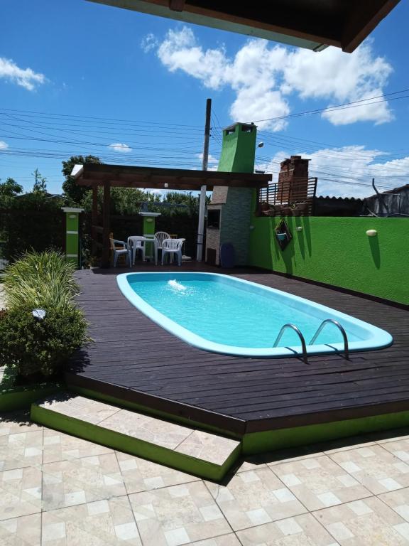 a swimming pool on a wooden deck next to a house at Casa com piscina no imbé in Imbé