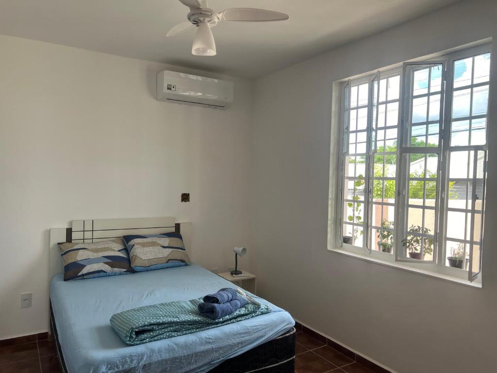 um quarto com uma cama, uma ventoinha de tecto e janelas em Suíte Príncipe Charles Ceres0021 em Cuiabá
