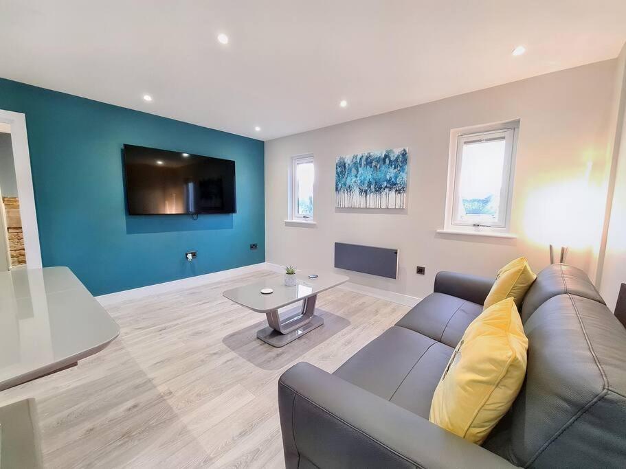 ein Wohnzimmer mit einem Sofa und einem Tisch in der Unterkunft Modern Luxury Apartment in Bishops Cleeve