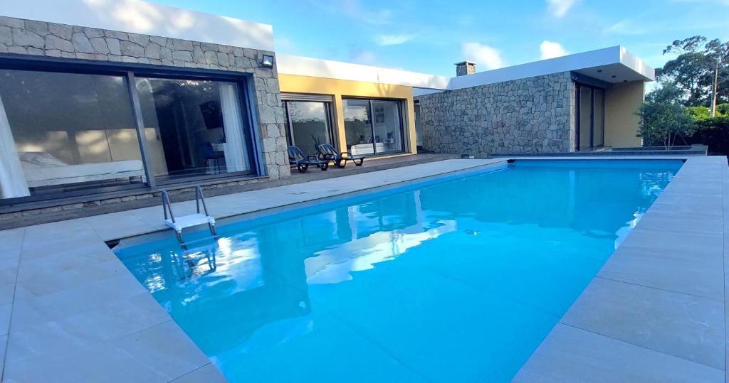 una piscina con acqua blu di fronte a una casa di Casa Azul Terceira Island Azores a Fonte do Bustardo
