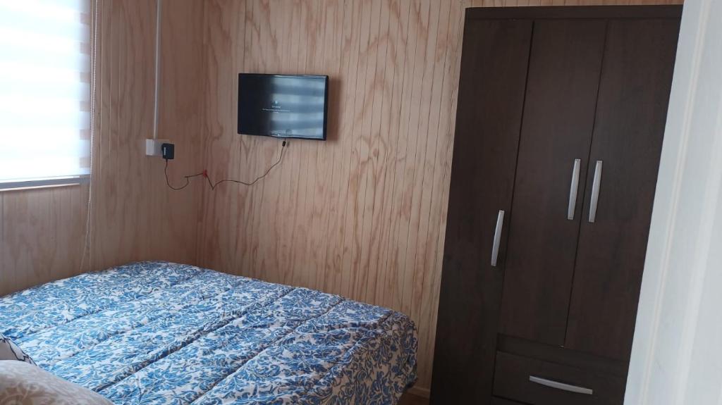 Un dormitorio con una cama y un televisor en una pared. en Cabaña Balmaceda - Puerto Montt, en Puerto Montt