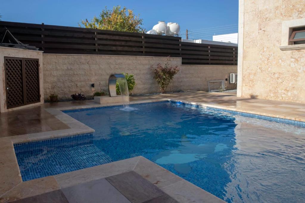 a swimming pool with blue water in front of a building at Luxury 5BR Private Villa with Pool - Paphos in Paphos
