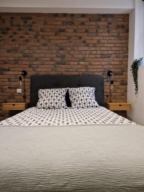 une chambre avec un lit avec un mur de briques dans l'établissement Suite dans l'hyper-centre de Rueil Malmaison, La Défense à 15 minutes, à Rueil-Malmaison