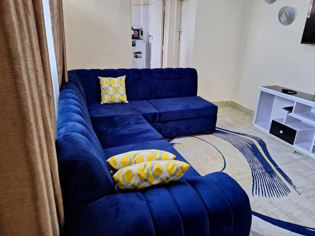 a blue couch with yellow pillows in a living room at Wema stays air Bnb in Naivasha