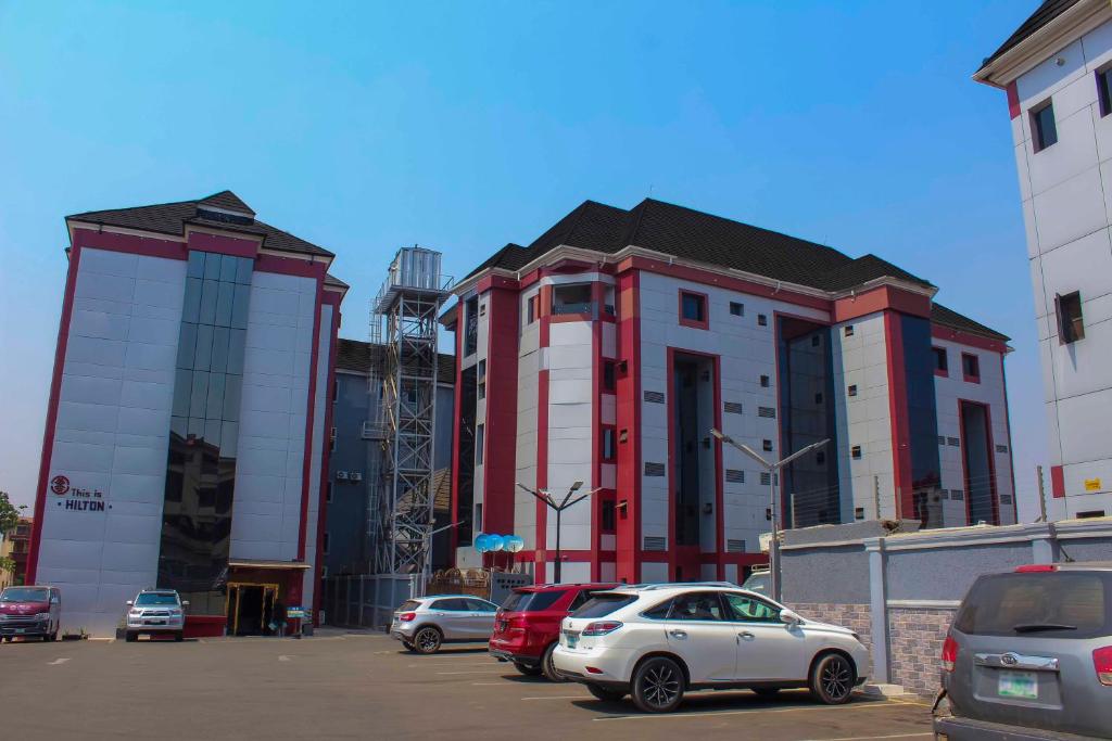 un estacionamiento con autos estacionados frente a un edificio en Hilton Leisure Resort en Awka