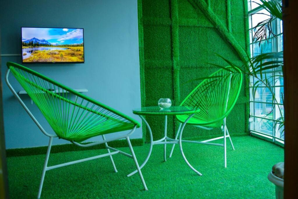 two green chairs and a table in a room at The Hidden gem Near Acacia Mall, 2 BDRs in Kampala
