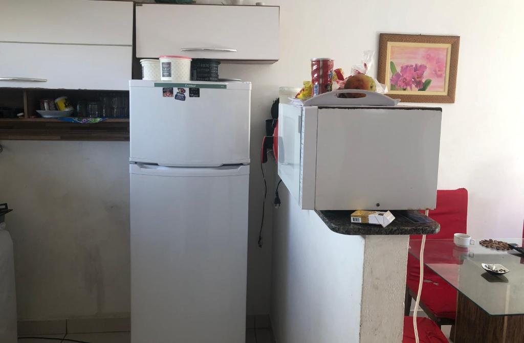 a white refrigerator in a kitchen with a microwave at House DayDrigo in Búzios