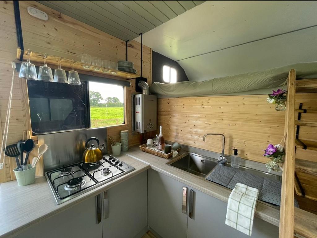 uma cozinha com um fogão e um lavatório numa caravana em North Yorkshire Horse Box em York