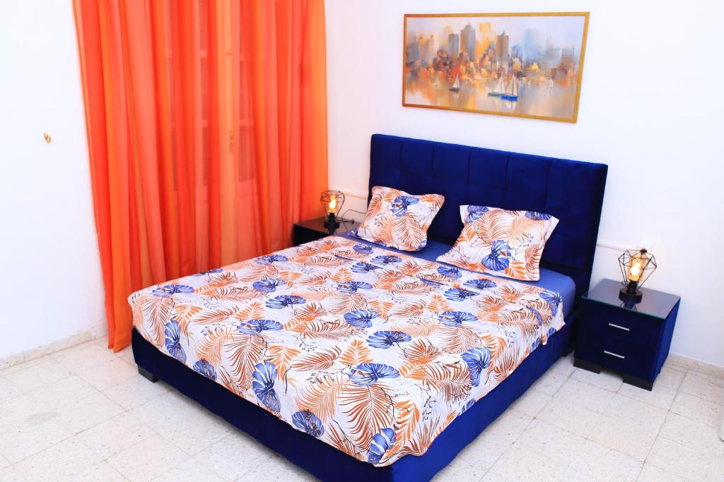 a bedroom with a blue bed with an orange curtain at Appartement Haut standing S+3 - plein centre ville in Tunis