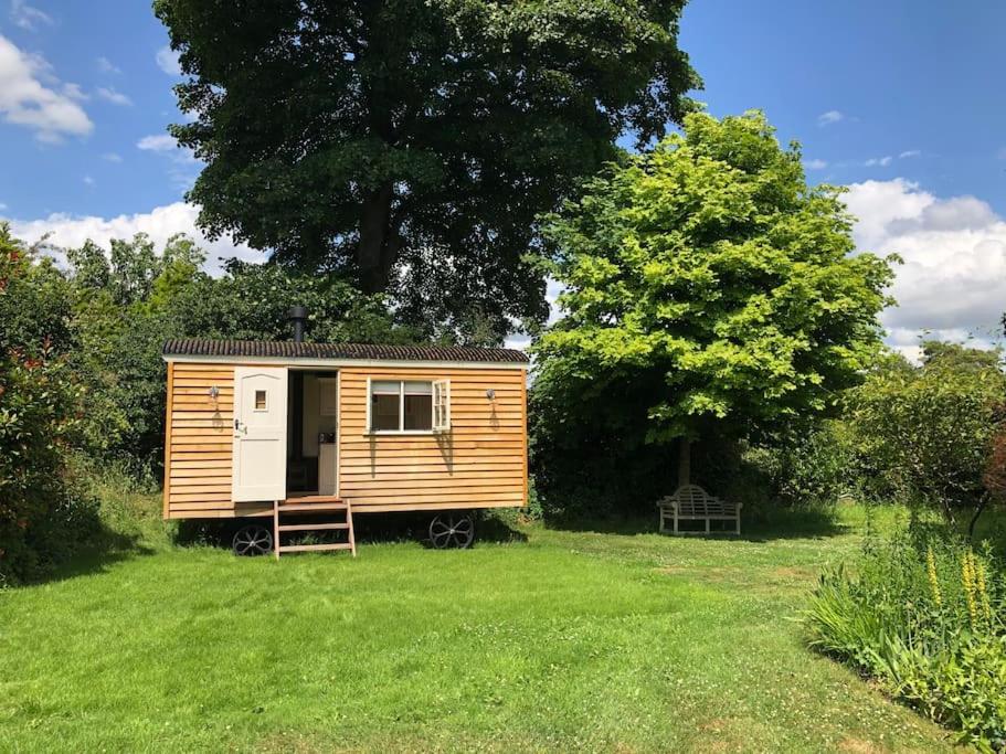 a wooden tiny house in a grassy field at The Old Vicarage Shepherd's Hut in Stroud