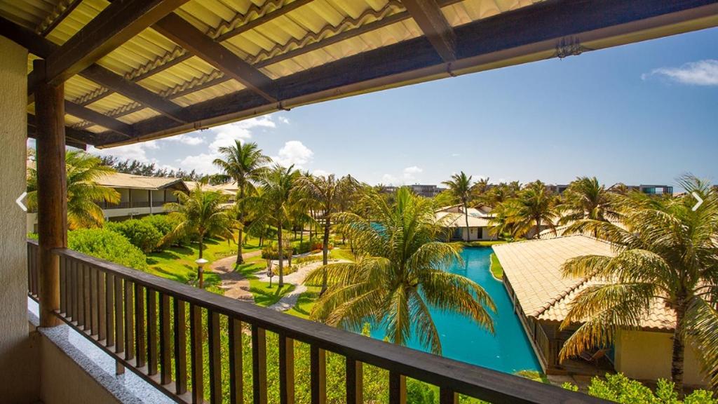 a balcony with a view of a pool and palm trees at Dom Pedro Laguna Beach Resort & Golf in Fortaleza