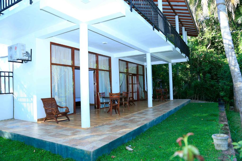 a patio with chairs and an umbrella on a house at River Edge Yala in Tissamaharama