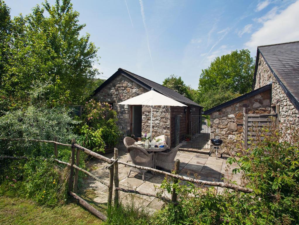 a stone house with a patio with an umbrella at 1 bed in Crickhowell 42953 in Llangattock