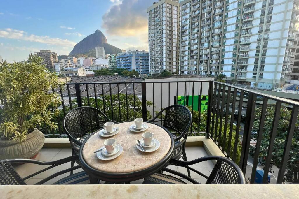 una mesa con tazas y platillos en el balcón en Lar da Abundância: Apartamento 3 Quartos no Leblon en Río de Janeiro